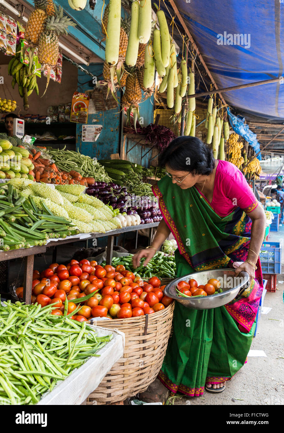 Donna indiana in sari raccoglie i pomodori da un cestello al mercato ortofrutticolo sul Palace Rd di Kochi, in India Foto Stock