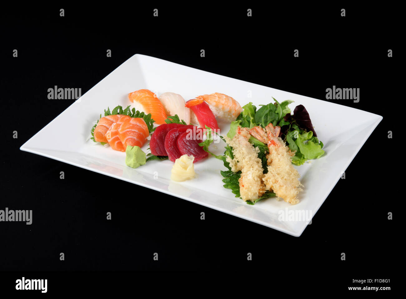 Il sushi e il sashimi con wasabi e vegetale in piastra bianca su sfondo nero Foto Stock
