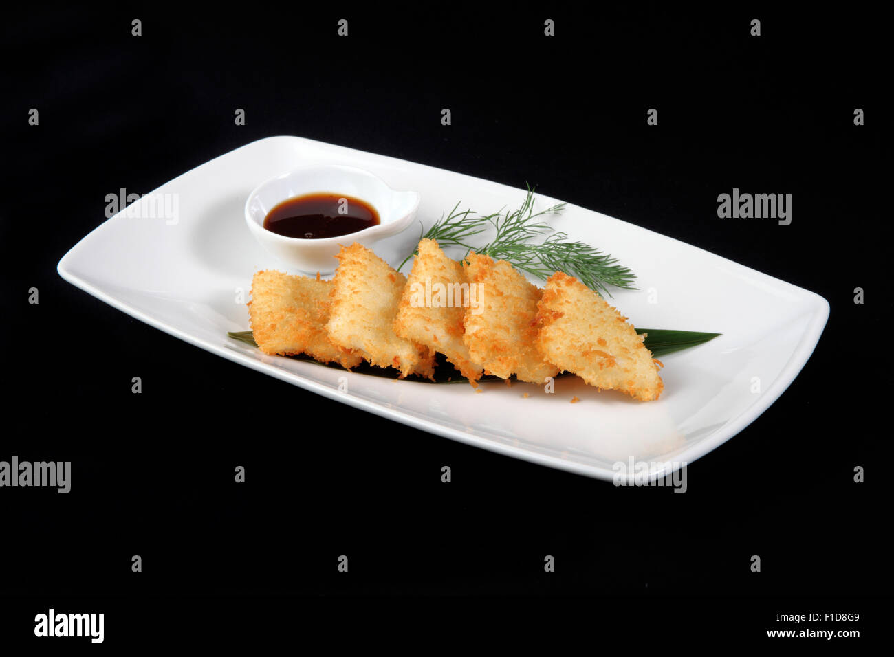 Calamari impanato nella piastra bianca su sfondo nero Foto Stock