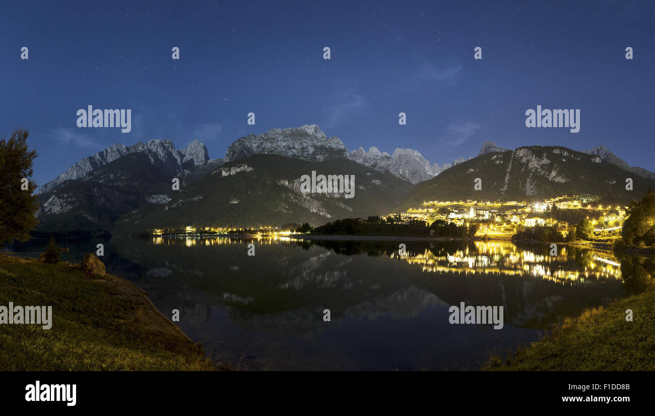 Paesaggio notturno sul lago Moveno e città con Dolomiti del Gruppo del Brenta in background al chiaro di luna Foto Stock