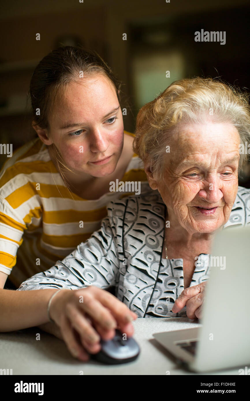 Ragazza giovane insegna donna anziana che lavora sul computer. La nipote con sua nonna vicino al computer. Foto Stock