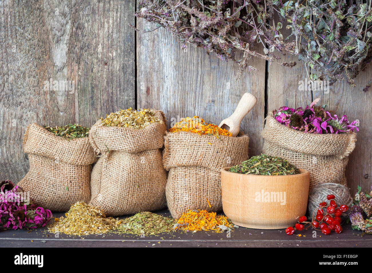 Secchi erbe curative in sacchetti di Hesse e nel mortaio sulla parete in legno sfondo, la medicina di erbe. Foto Stock