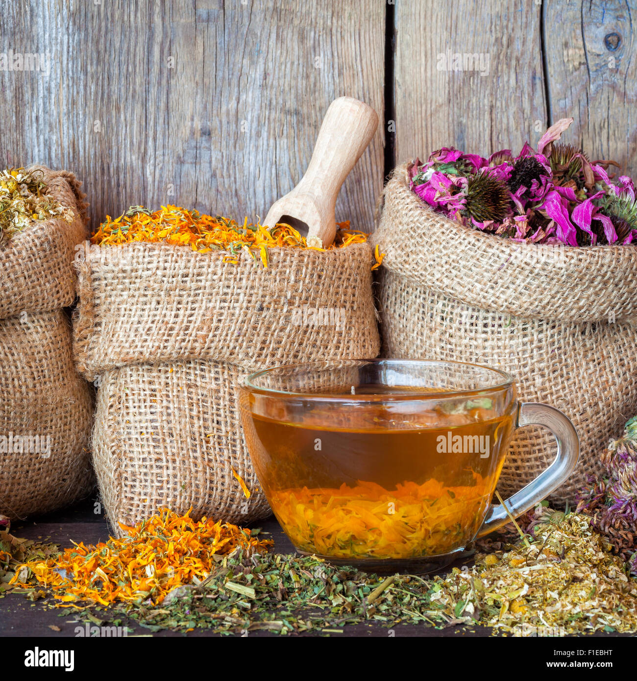 Erbe curative in sacchetti di Hesse e sana tazza di tè in legno rustico sfondo, la medicina di erbe. Foto Stock
