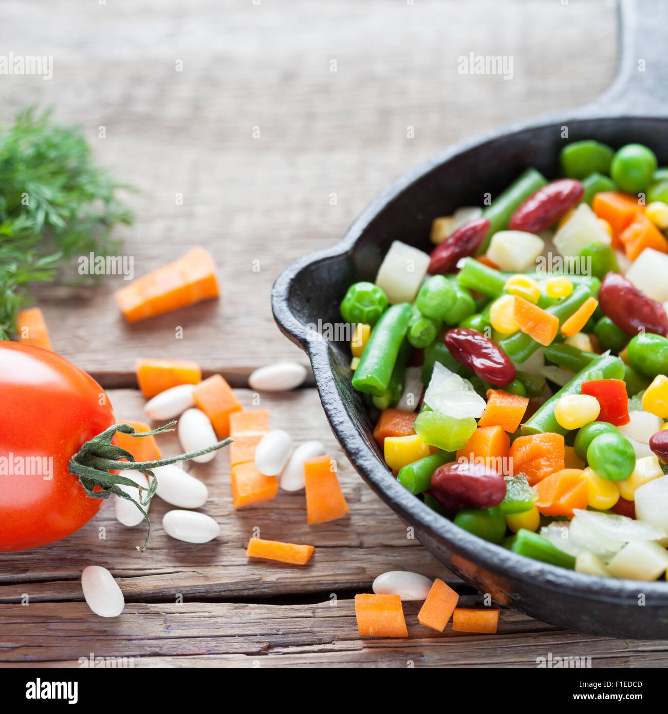 Verdure miste pasto nella vecchia padella closeup e ingredienti su legno tavolo rustico. Foto Stock