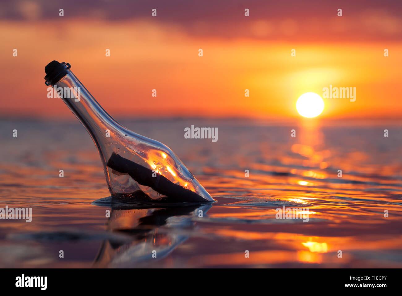 Bottiglia con un messaggio in mare al tramonto Foto Stock
