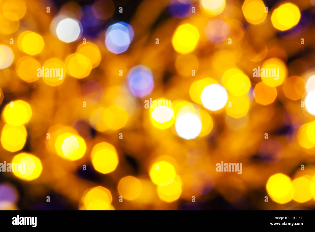 Abstract sfocare lo sfondo scuro - giallo e viola scintillanti luci di Natale bokeh di le ghirlande elettriche su albero di Natale Foto Stock