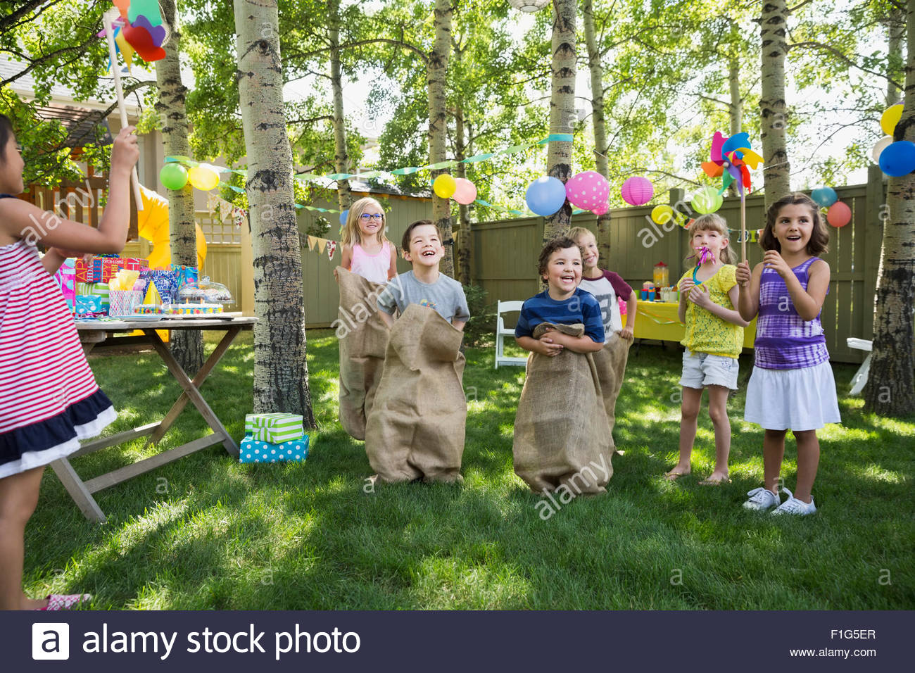 Kids godendo il sacco gara a backyard festa di compleanno Foto Stock