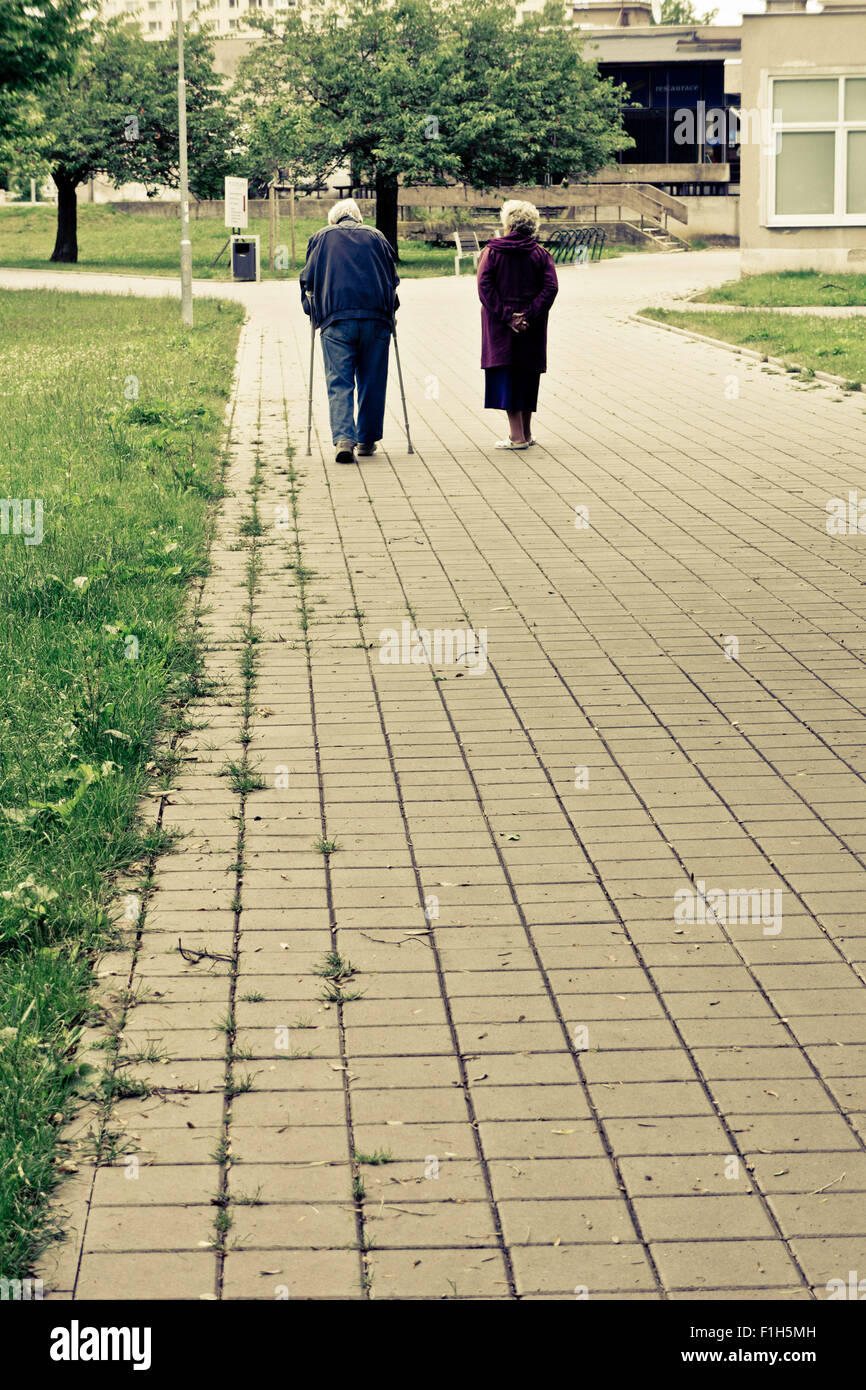 Coppia di anziani a piedi, l'uomo su stampelle Foto Stock