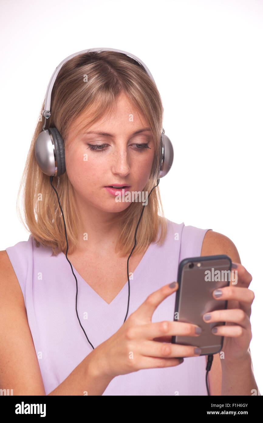 Donna bionda che indossa le cuffie per ascoltare musica sul suo telefono. Foto Stock