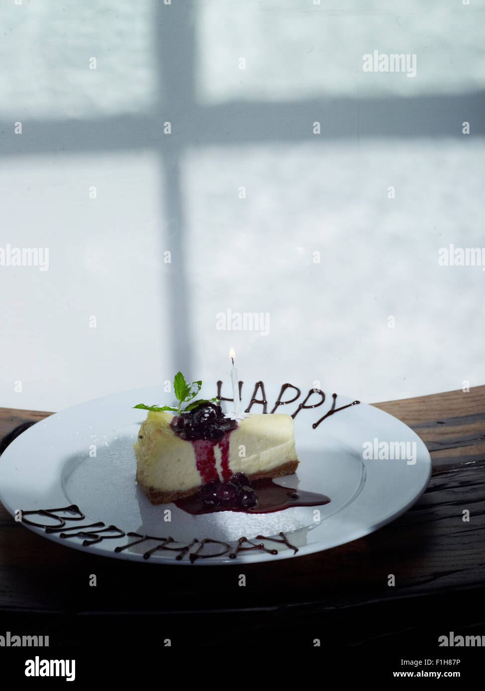 Una fetta di torta di compleanno su una piastra che era stato decorato con "Happy Birthday" scritto in salsa. Foto Stock