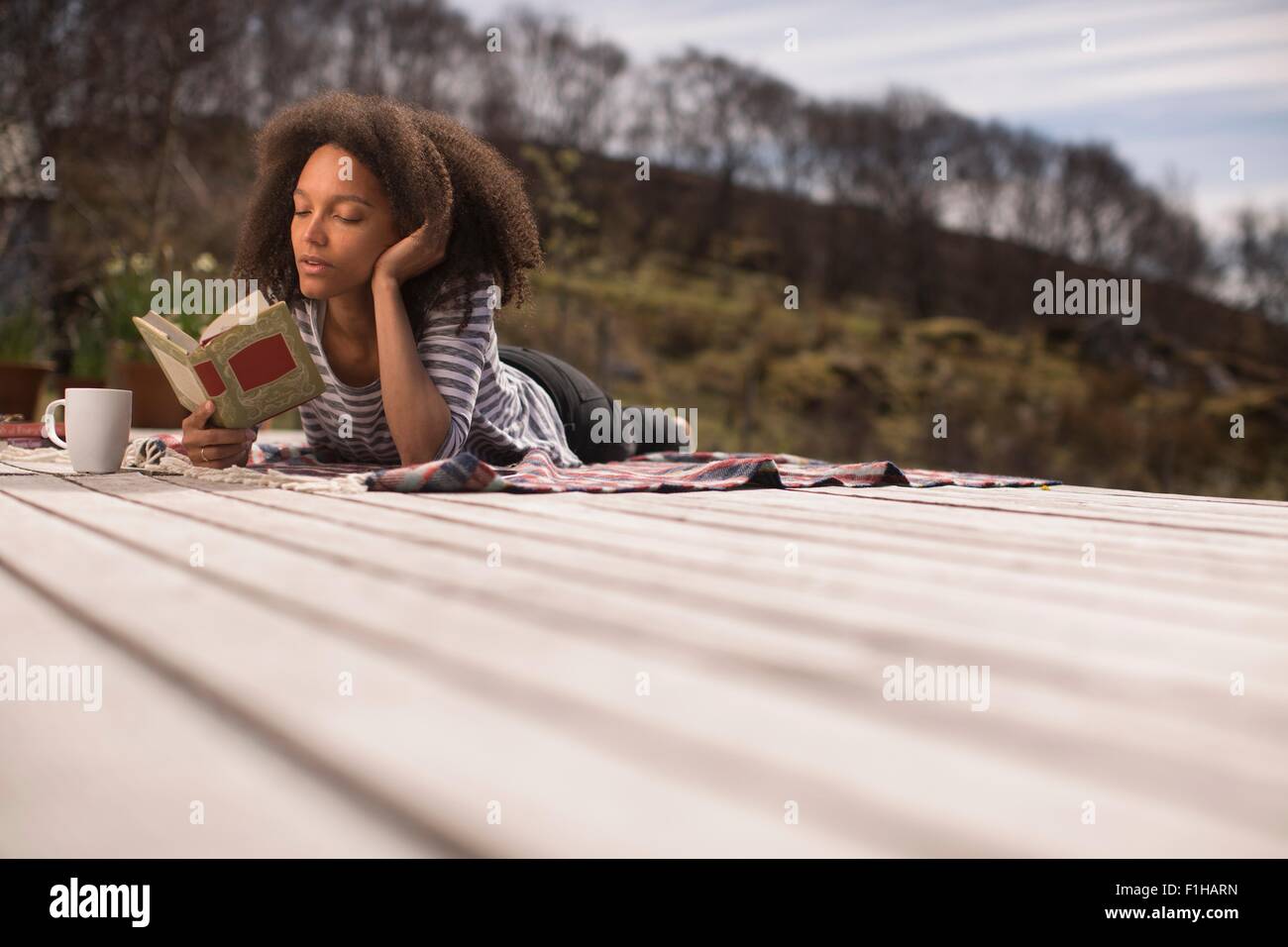 Metà donna adulta sdraiato, libro di lettura Foto Stock