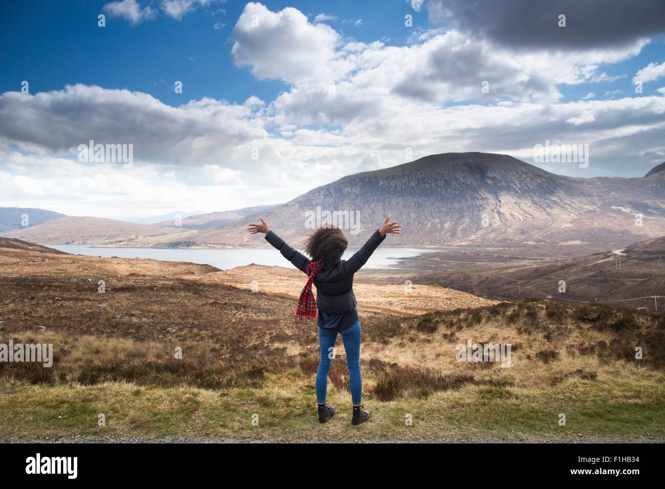 Metà donna adulta in montagna con le braccia in alto, Isola di Skye, Ebridi, Scozia Foto Stock