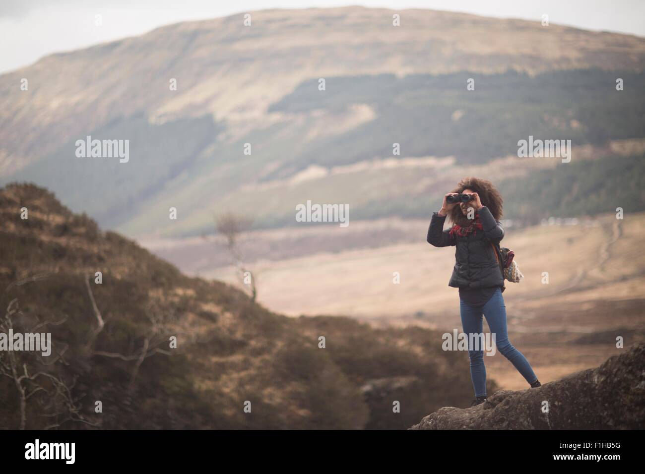 Donna che utilizza un binocolo, Fata Piscine, Isola di Skye, Ebridi, Scozia Foto Stock