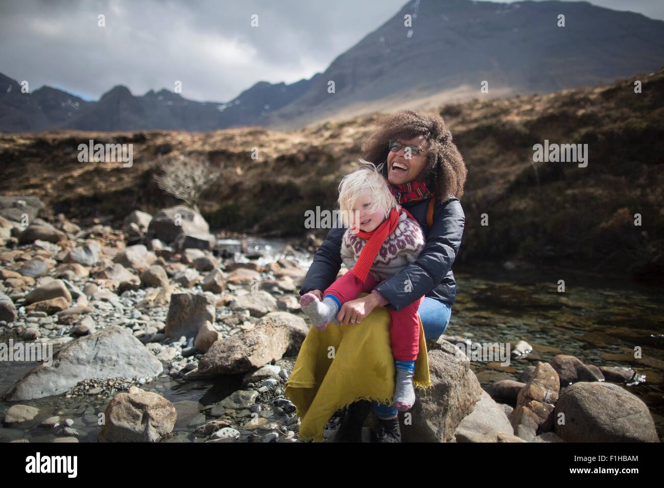 Madre e figlio seduti sulle rocce, Fairy Piscine, Isola di Skye, Ebridi, Scozia Foto Stock