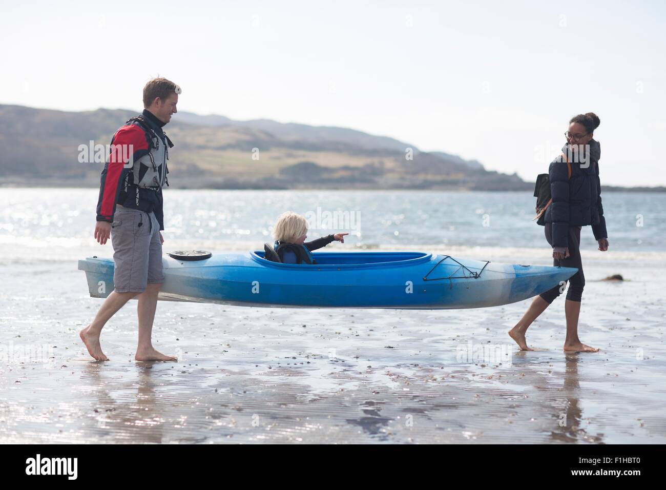 I genitori che trasportano il figlio in canoa sulla spiaggia, Loch Eishort, Isola di Skye, Ebridi, Scozia Foto Stock