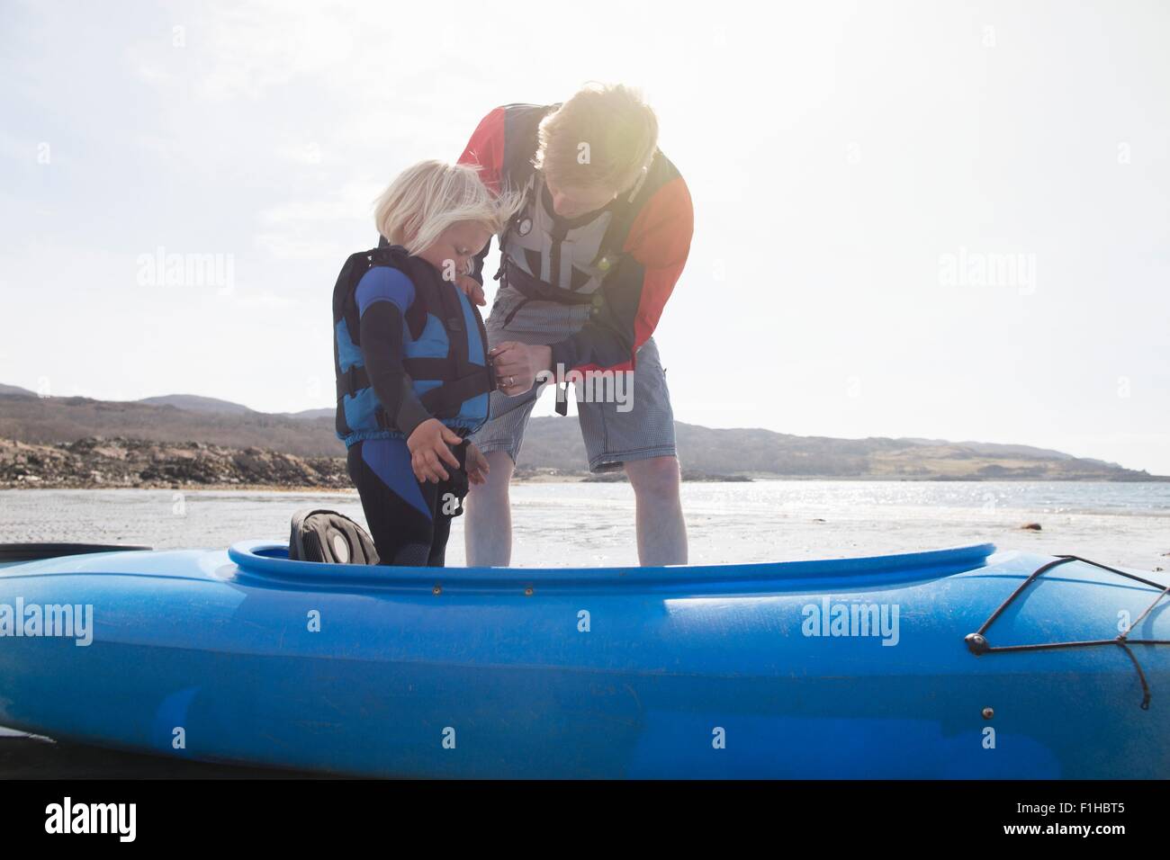 Padre aiutando figlio regolare giubbotto di salvataggio in canoa, Loch Eishort, Isola di Skye, Ebridi, Scozia Foto Stock