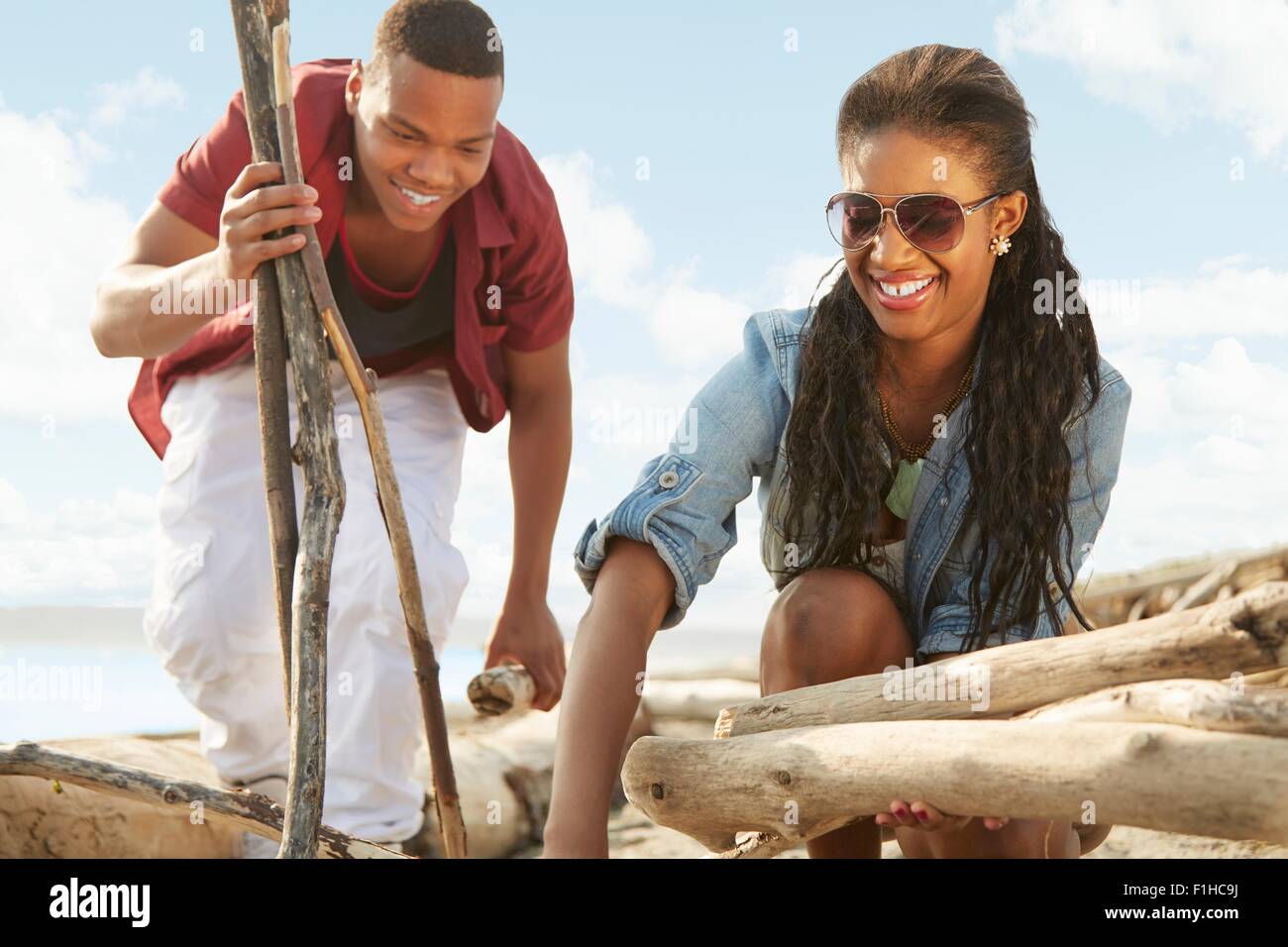 Coppia giovane sulla spiaggia raccolta driftwood insieme Foto Stock