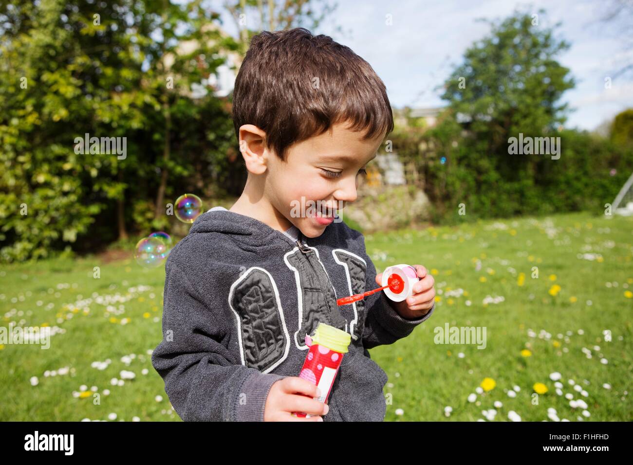 Ritratto di ragazzo soffiare bolle in giardino Foto Stock