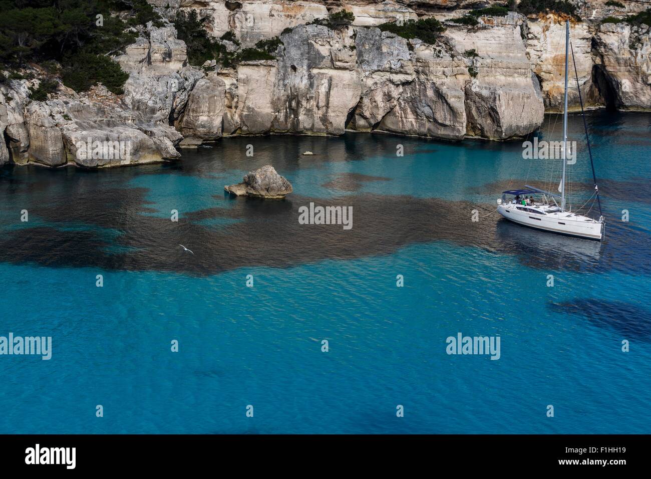 Scogliere di Cala Macarella e barca a vela, Menorca, Spagna Foto Stock