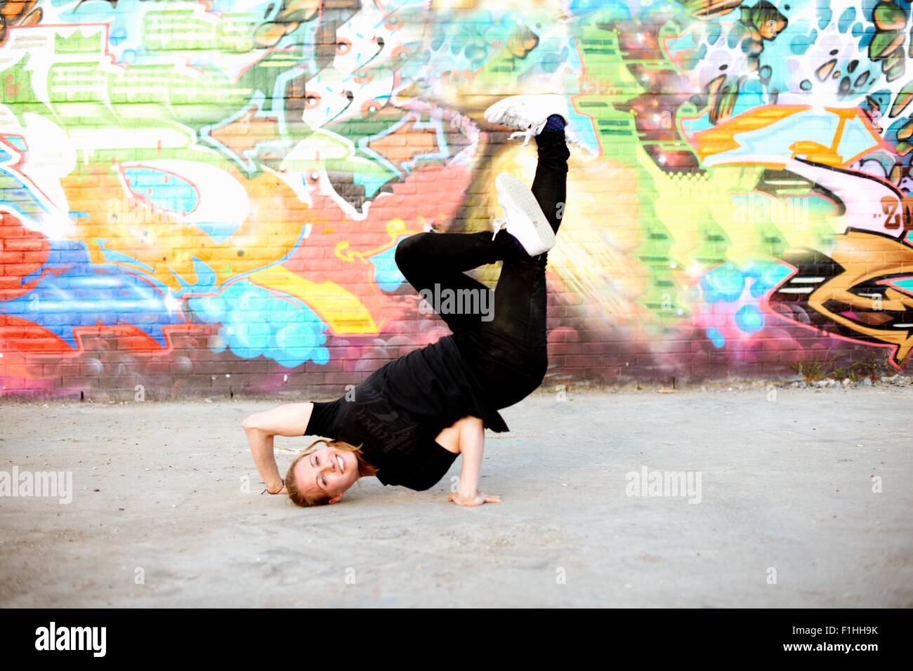Giovane donna in capovolto breakdance congelare contro graffiti Foto Stock