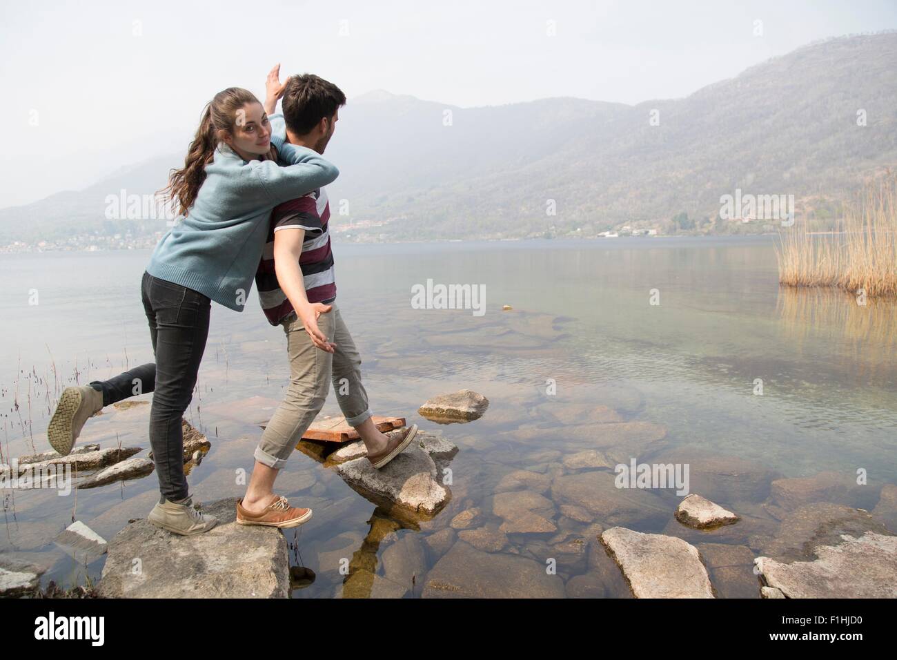 Giovane stepping sulle rocce in riva al Lago di Mergozzo, Provincia di Verbania, Piemonte, Italia Foto Stock