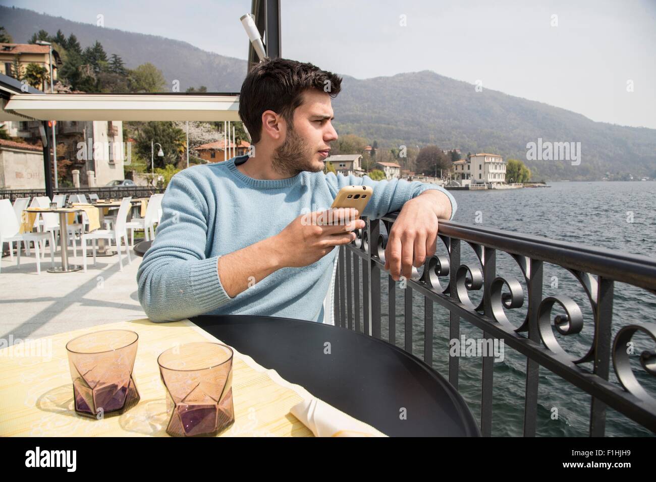 Giovane uomo guardando fuori dal ristorante sul lago, il Lago di Mergozzo, Provincia di Verbania, Piemonte, Italia Foto Stock