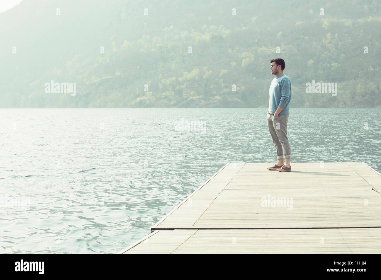 Giovane uomo guardando fuori dal molo, Lago di Mergozzo, Provincia di Verbania, Piemonte, Italia Foto Stock