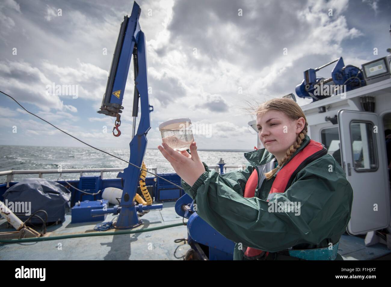 Donna scienziato ispezione campione di plancton sulla nave per la ricerca Foto Stock