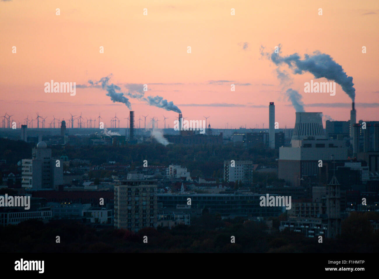 Luftbild: Blick ueber Berlin, im Hintergrund rauchende Schornsteine eines Kraftwerks und dahinter eine Phalanx aus Windkraftraed Foto Stock