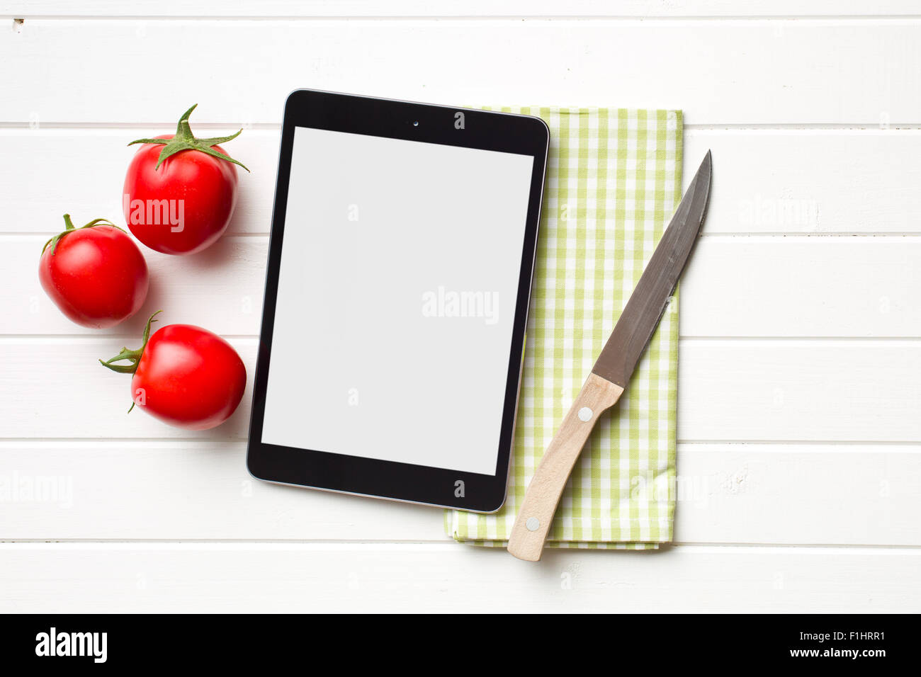 Computer tablet e pomodori sul tavolo da cucina Foto Stock