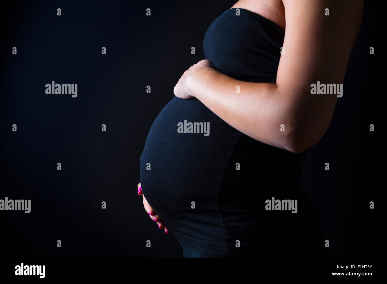 Donna in stato di gravidanza sta con le mani in corrispondenza del ventre Foto Stock