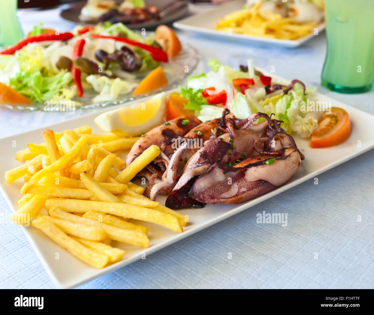 Calamari alla griglia con patate fritte e insalata mista Foto Stock