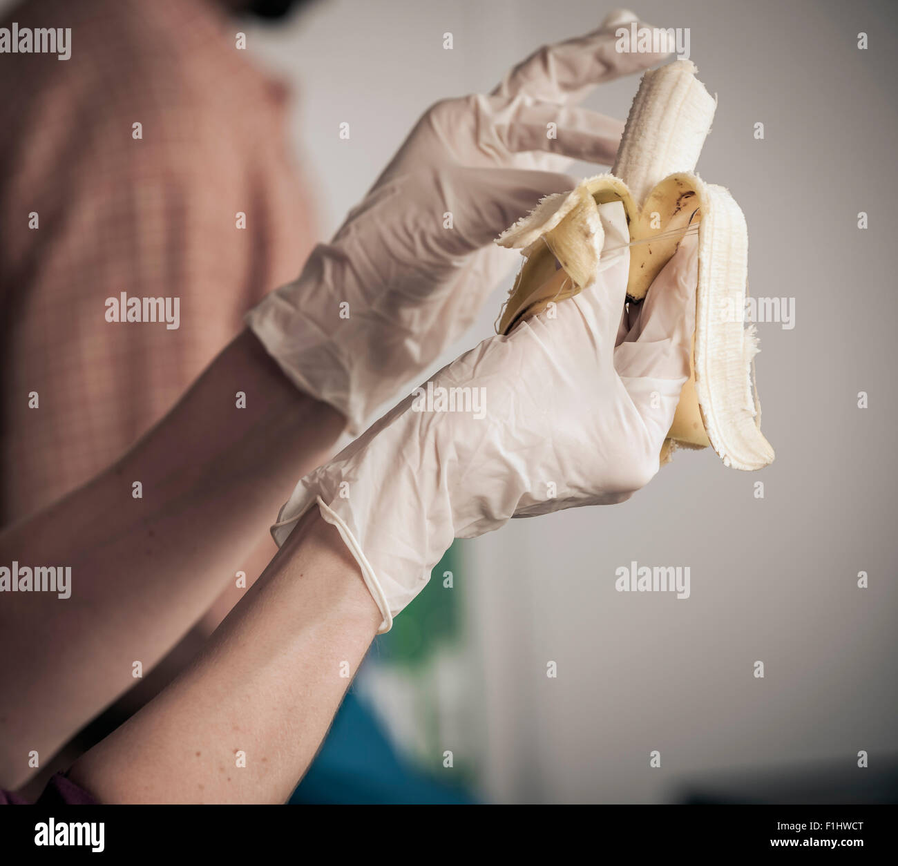 Persona che mangia il banana con guanti in Foto Stock