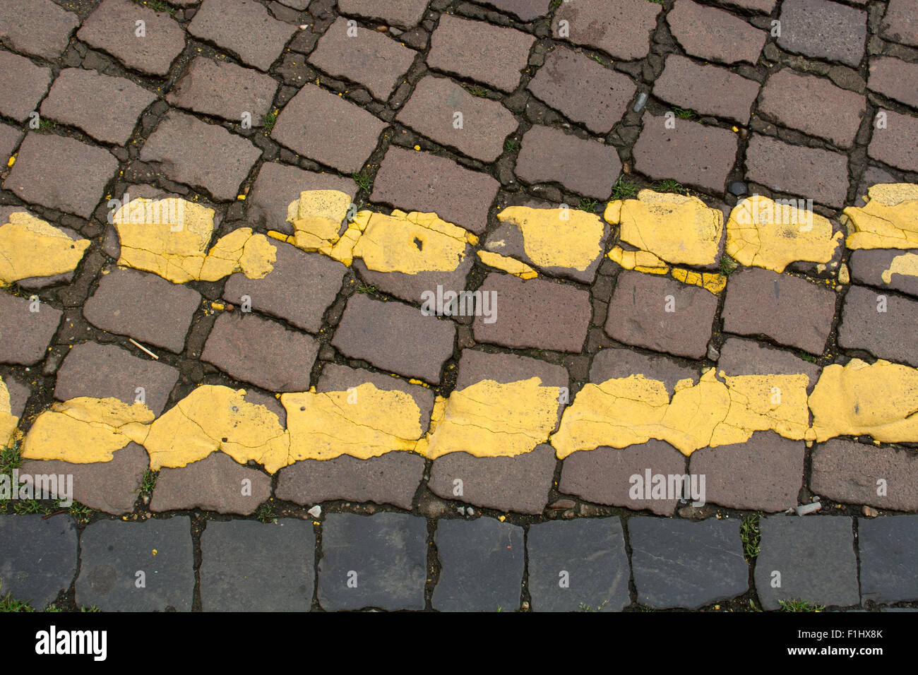 Doppio giallo linee su una strada basolata superficie, REGNO UNITO Foto Stock