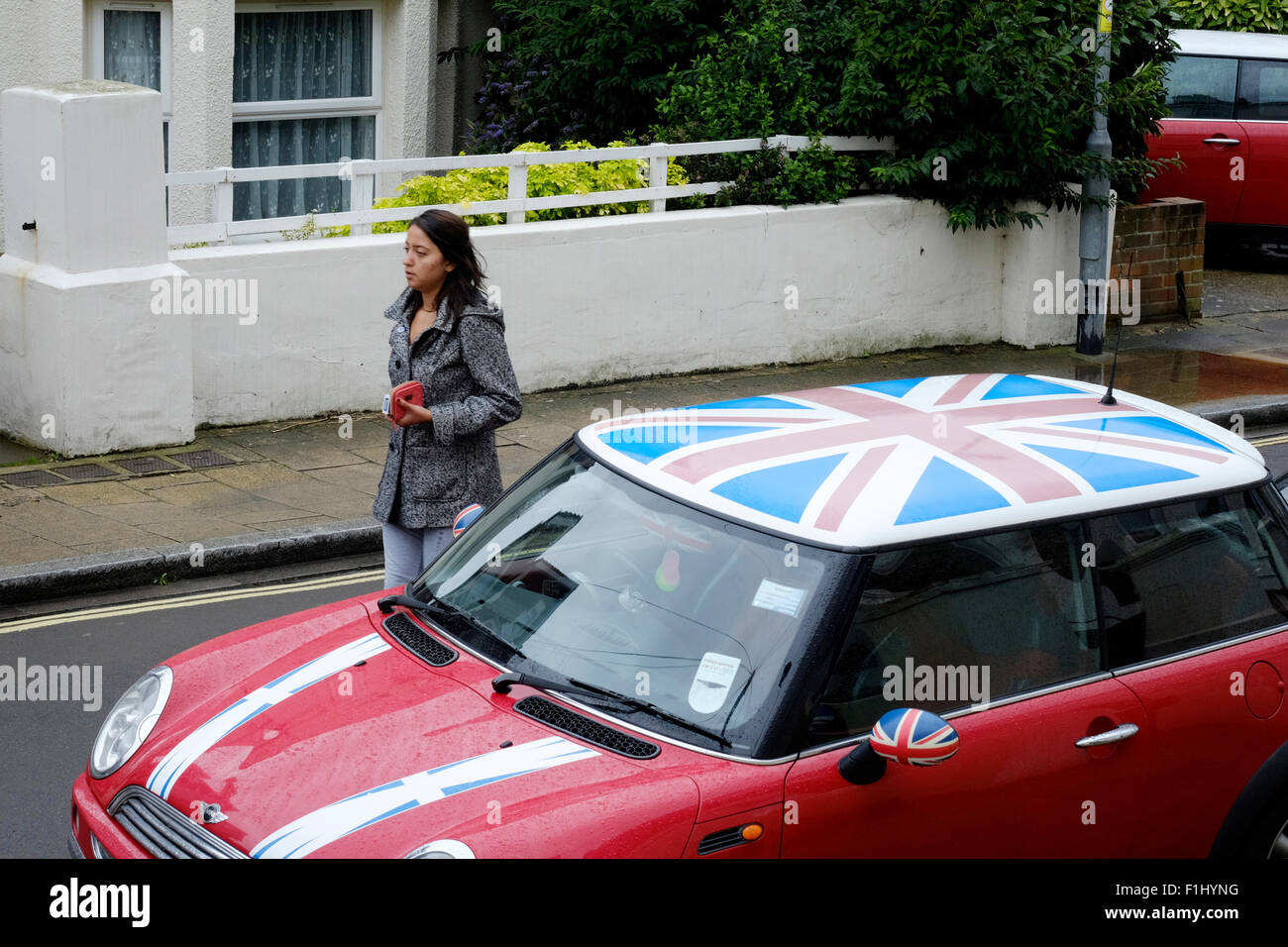 Giovani donne a piedi in strada oltre un mini auto finito in una unione di design di bandiera Inghilterra Regno Unito Foto Stock