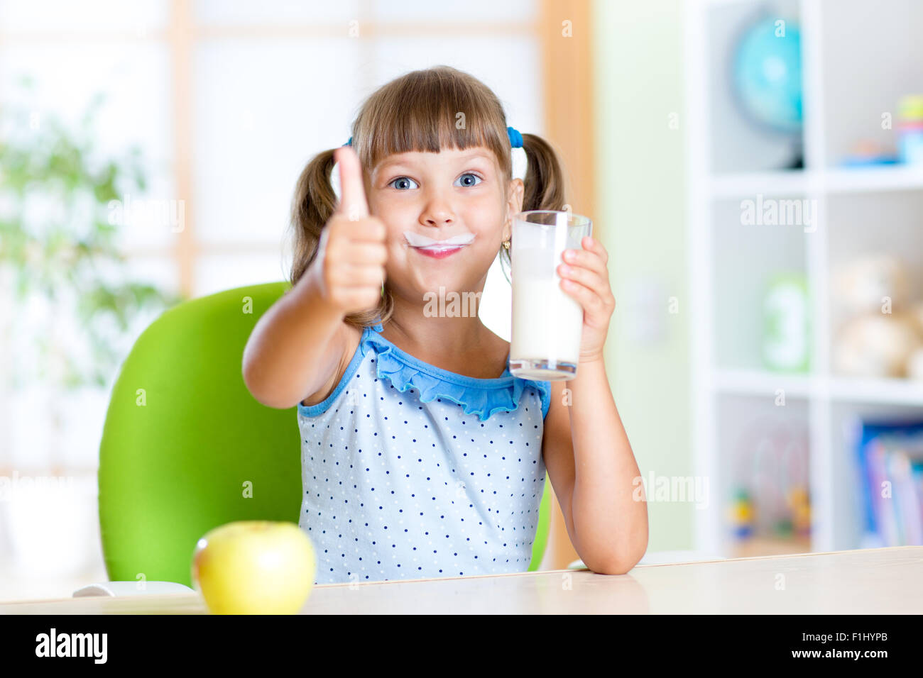 Bambino beve latte e mostrando il pollice in alto Foto Stock
