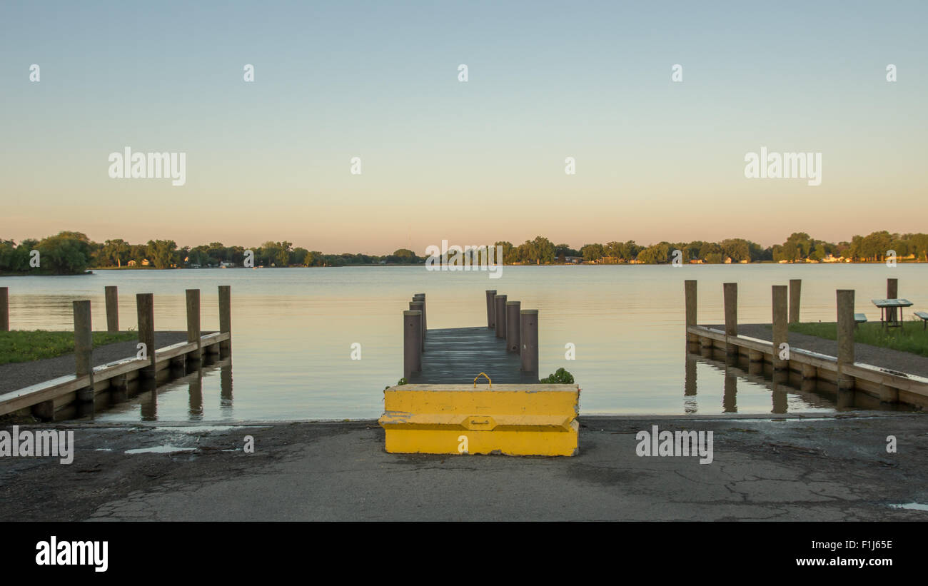Una barca lancio / sbarco all'alba, accanto alle tranquille acque calme di un lago. Foto Stock