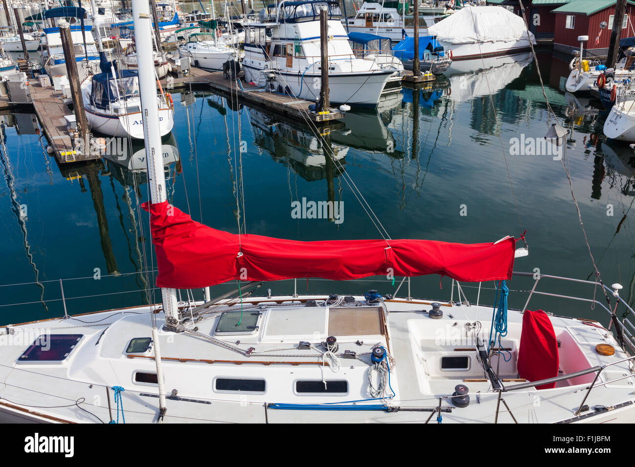 Piccolo yacht con una vibrante red sail coperchio in una marina su false creek, Vancouver Foto Stock