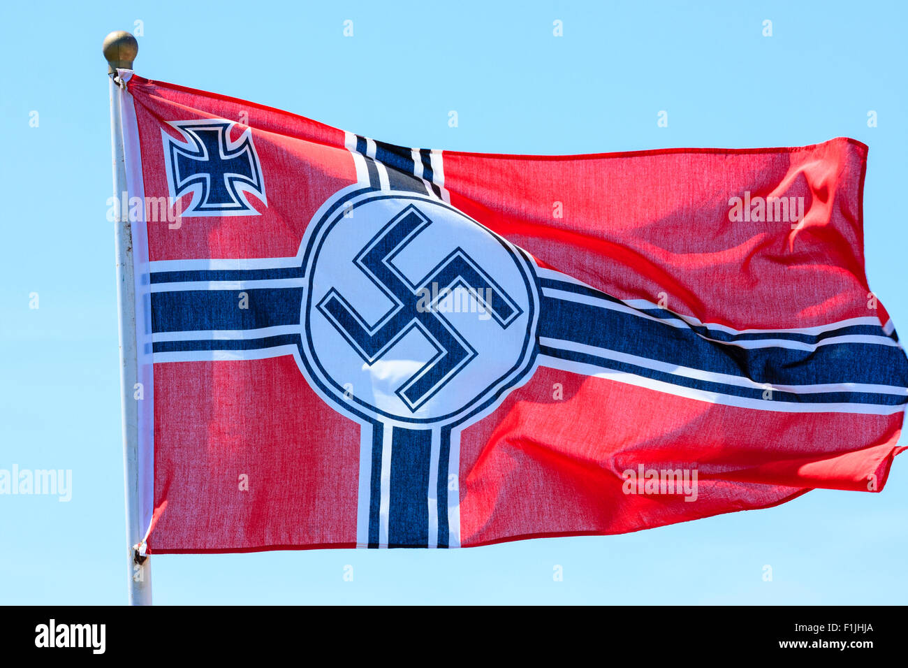 Seconda guerra mondiale esercito tedesco bandiera che fluttua nel vento con cielo blu chiaro dello sfondo. Croce tedesca con la svastica nazista in centro e angolo croce di ferro. Foto Stock