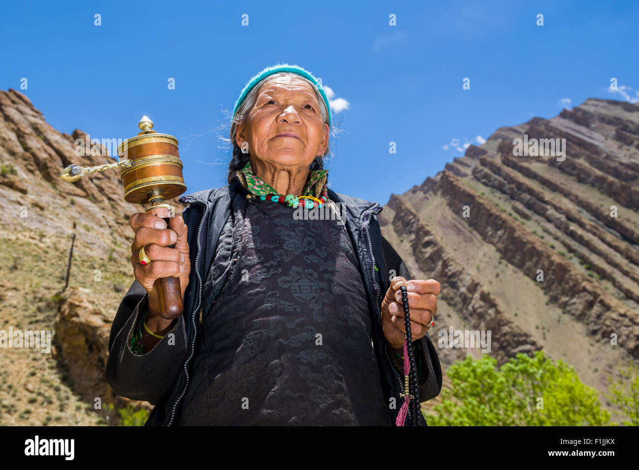 Una vecchia donna Ladakhi è in rotazione una ruota di preghiera, Hemis Gompa, Hemis, Jammu e Kashmir India Foto Stock