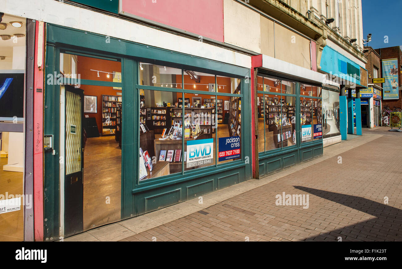 Negozio di vuoto con manifesti in windows per renderlo meno abbandonate su un high street a West Bromwich, West Midlands, Inghilterra. Foto Stock