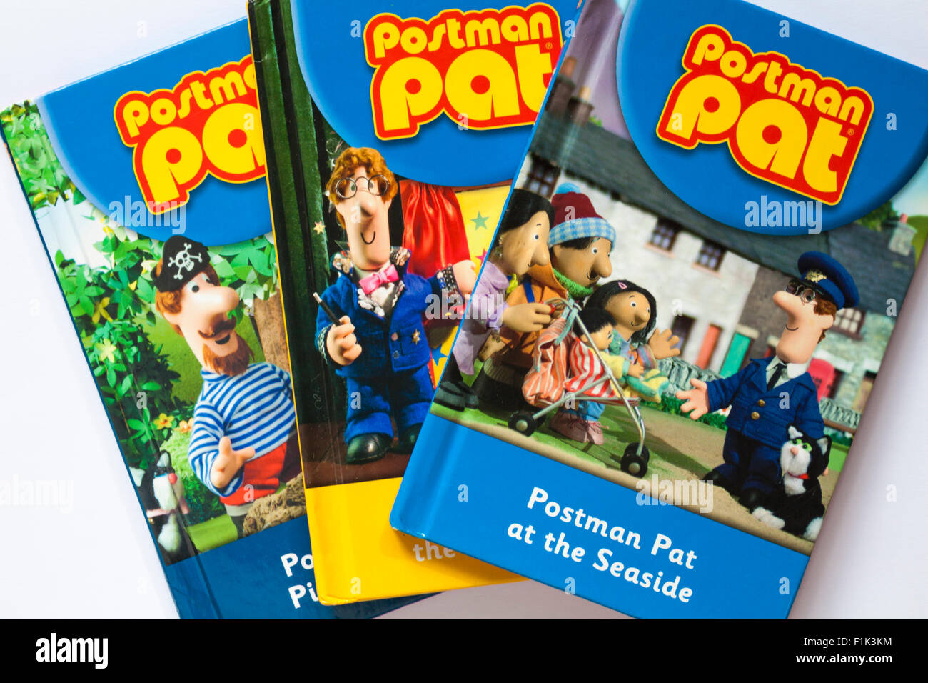 Tre portalettere Pat libri per bambini con il postino Pat al mare prenota sulla parte superiore impostato su sfondo bianco Foto Stock