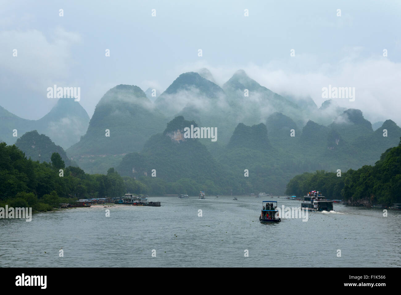 Piccole imbarcazioni e le navi da crociera sul fiume Li in Cina contro montagne trascendentale e vegetazione tropicale Foto Stock