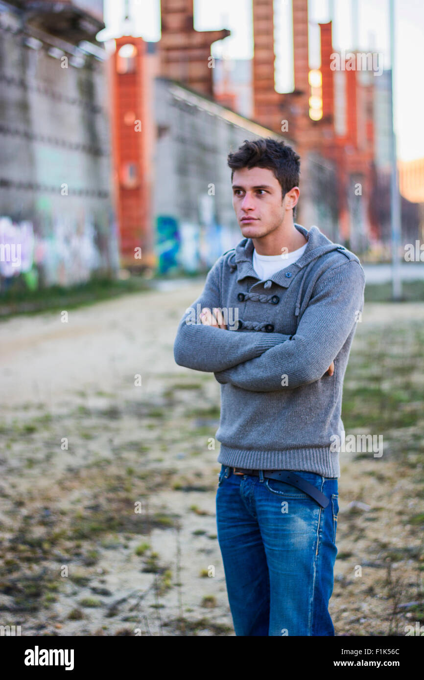 Attraente giovane uomo in ambiente urbano in piedi con le braccia incrociate sul petto Foto Stock