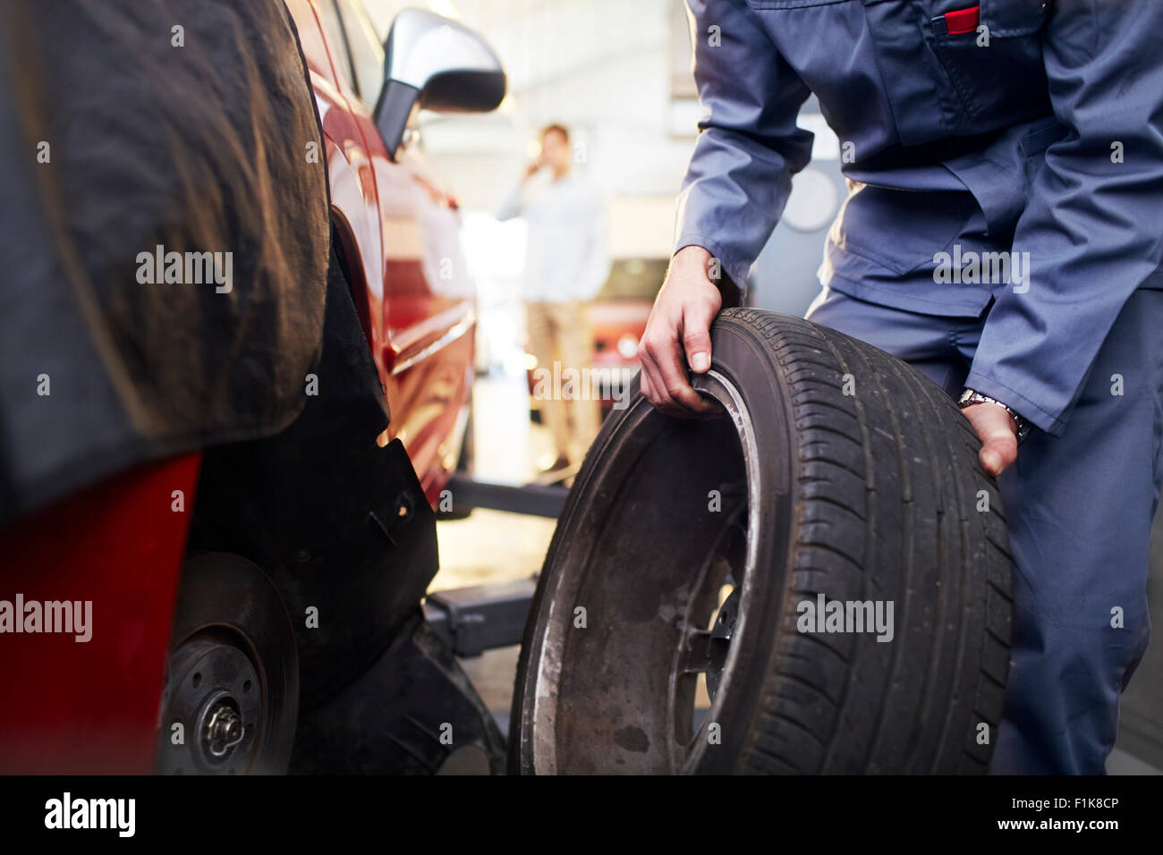 Meccanico di pneumatici di sostituzione in negozio di riparazioni auto Foto Stock