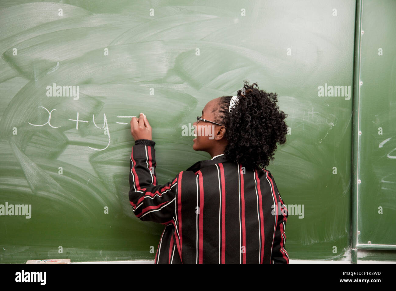 Una femmina di alta scuola studente iscritto su una lavagna Foto Stock