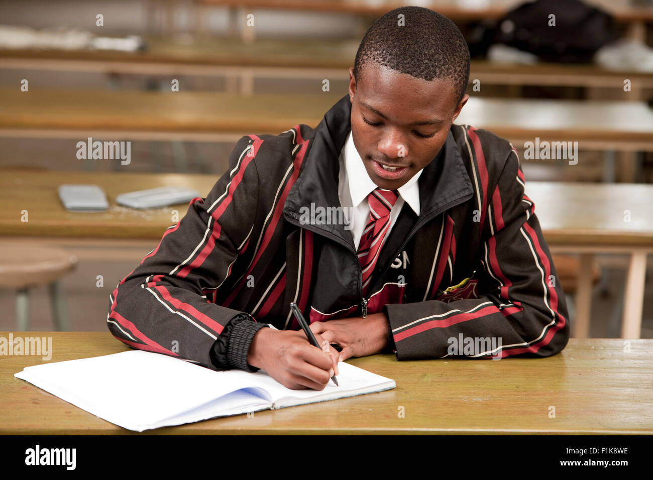 Un maschio di studente di scuola superiore al lavoro presso la sua scrivania Foto Stock