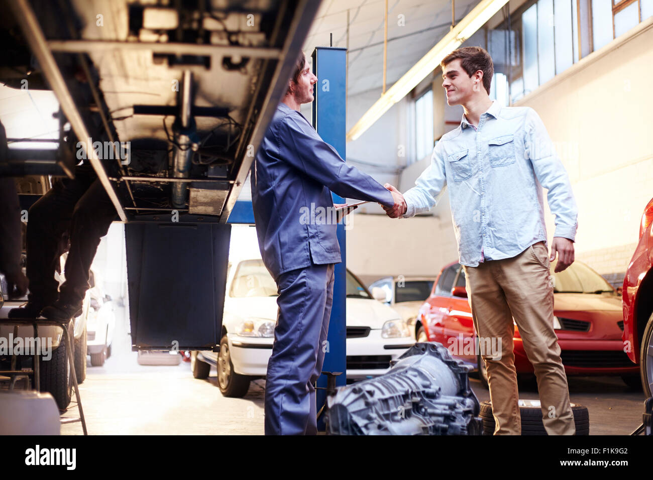 Meccanico e di handshaking del cliente in negozio di riparazioni auto Foto Stock