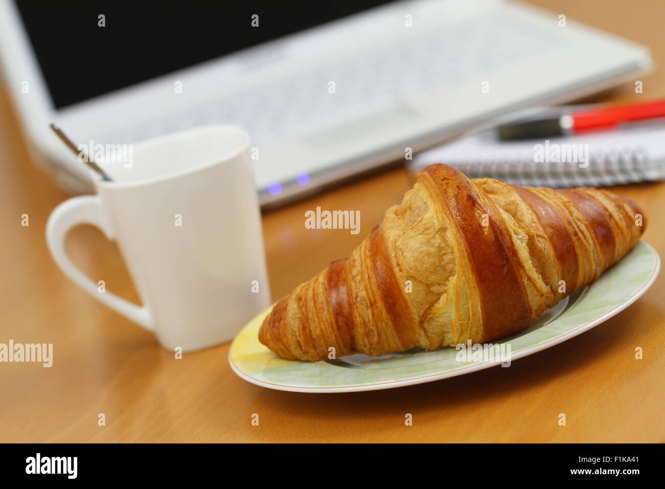Croissant al burro e caffè sulla scrivania in ufficio Foto Stock