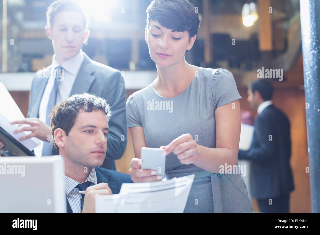 La gente di affari guardando il cellulare in ufficio Foto Stock